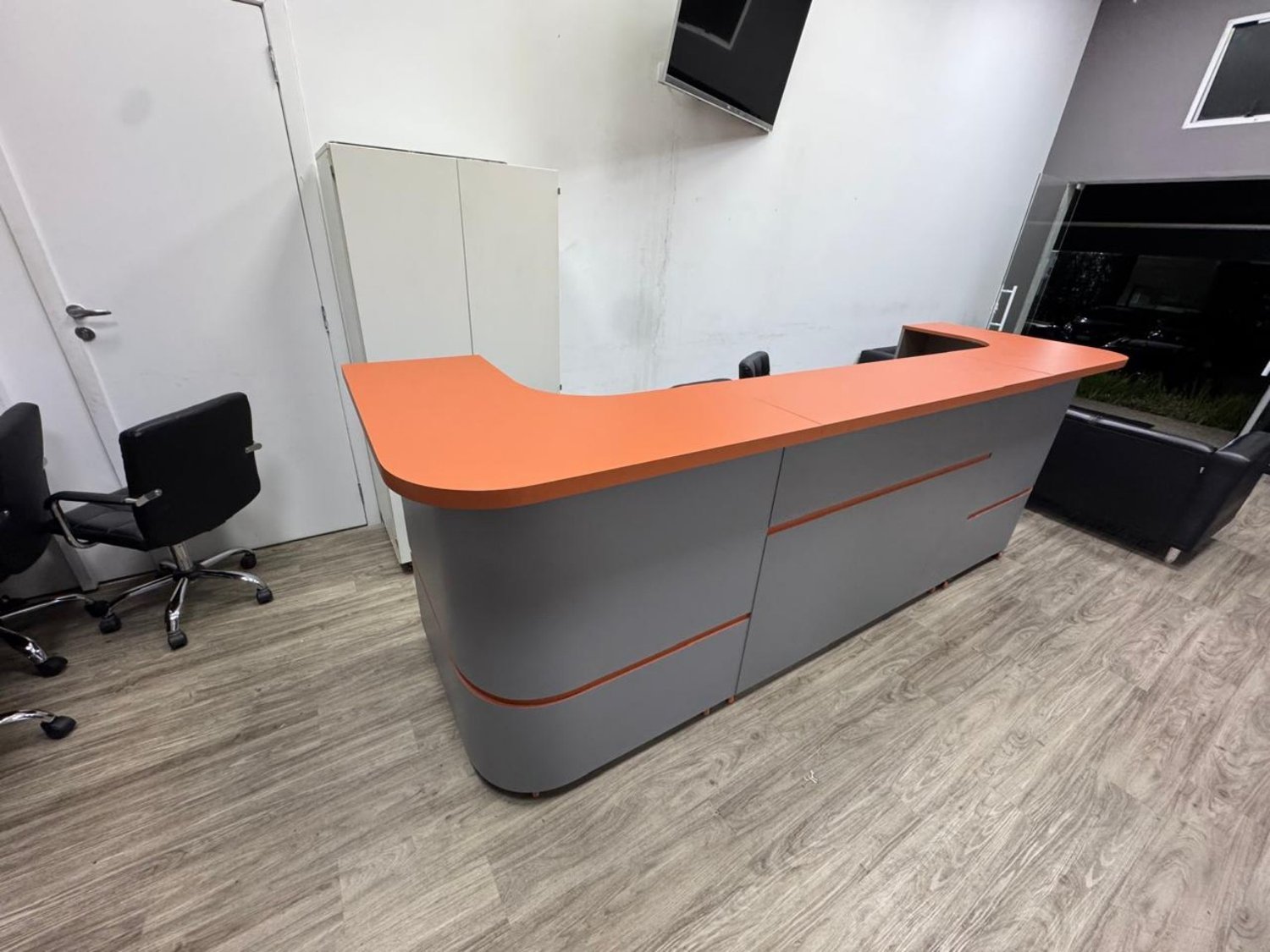 Balcão de recepção com tampo laranja e acabamento cinza