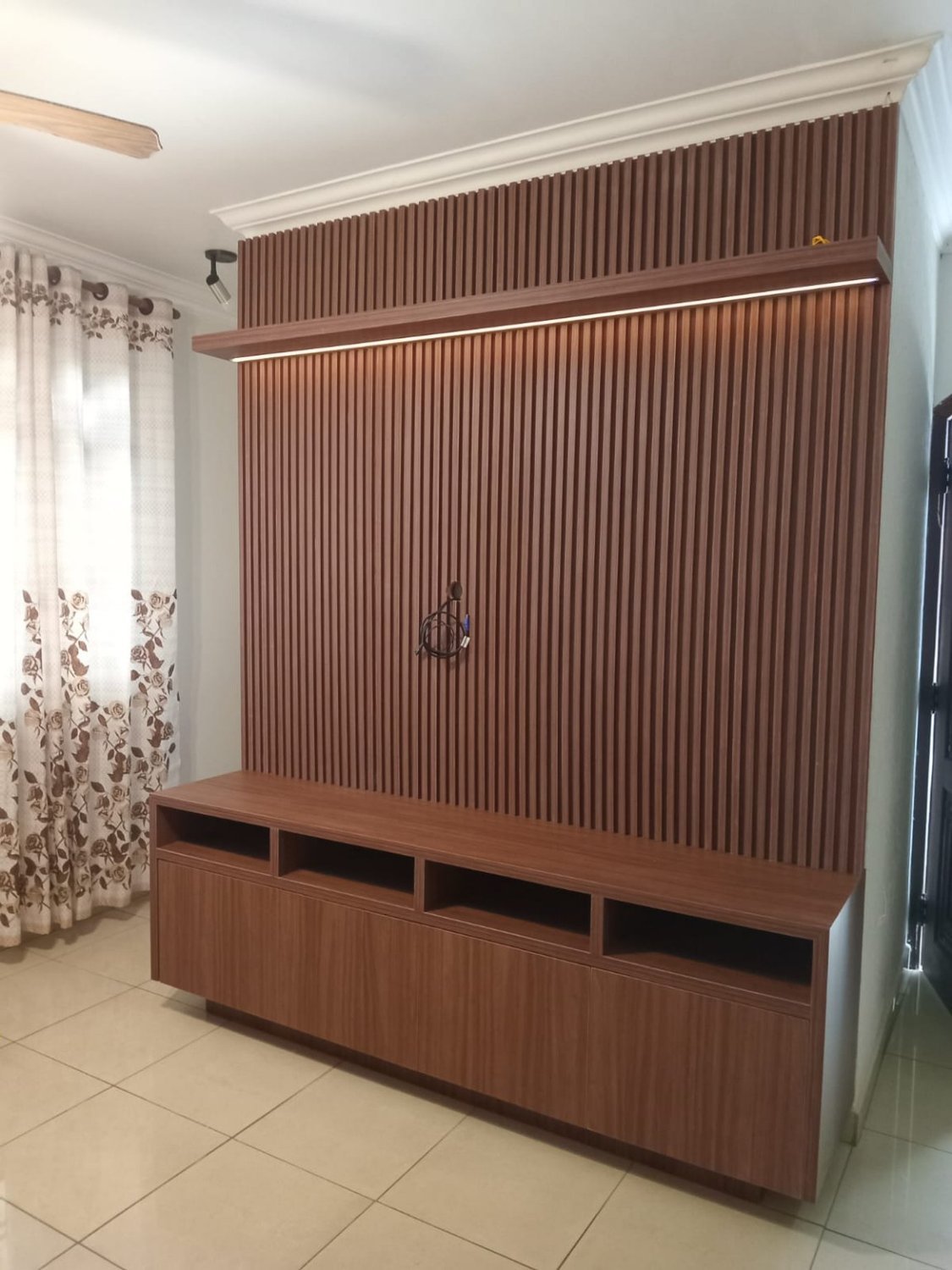 Painel ripado de madeira com móvel de TV e iluminação linear